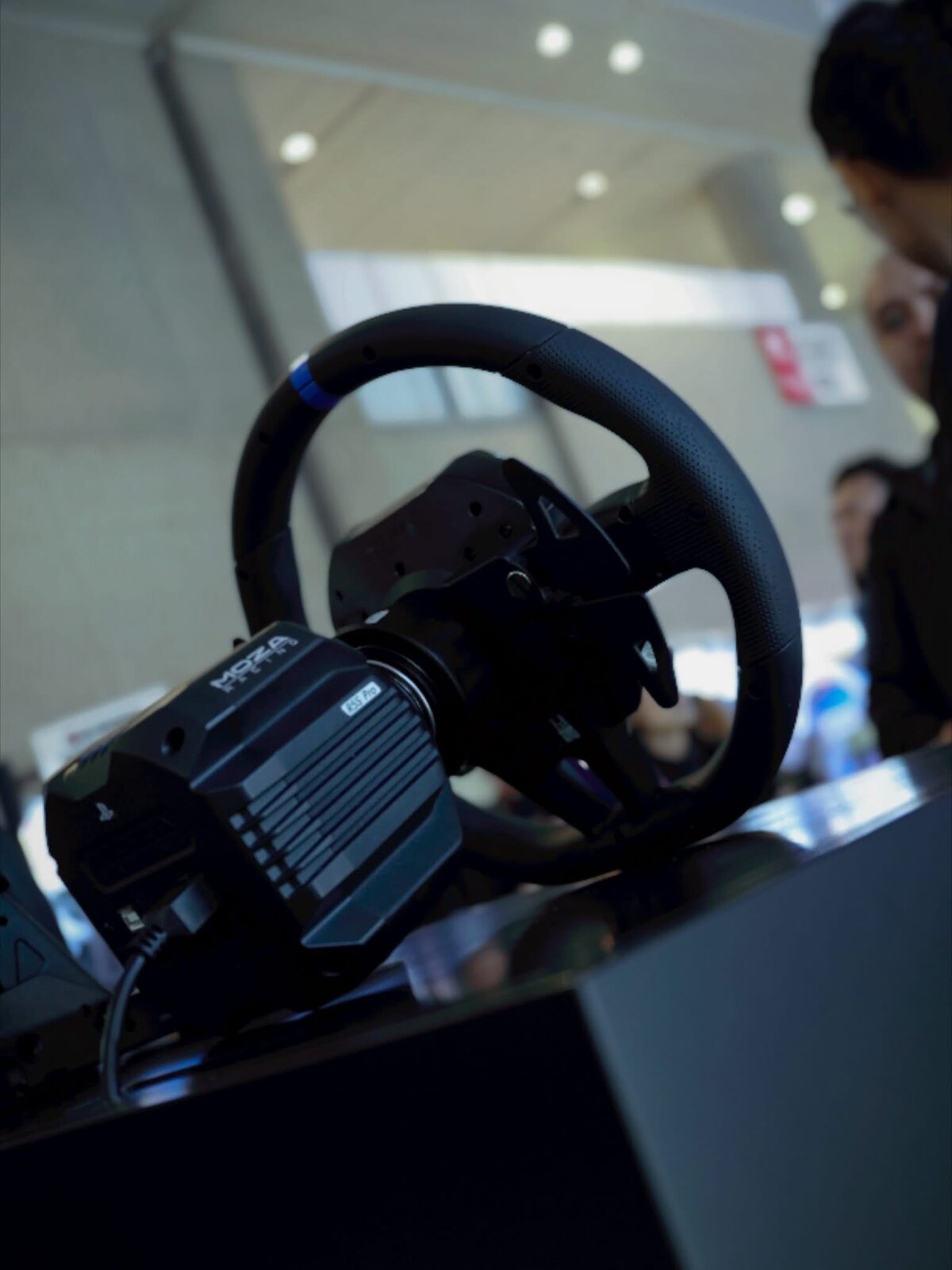 La base Moza R5S Pro avec son volant monté, logo PlayStation visible en façade du boîtier