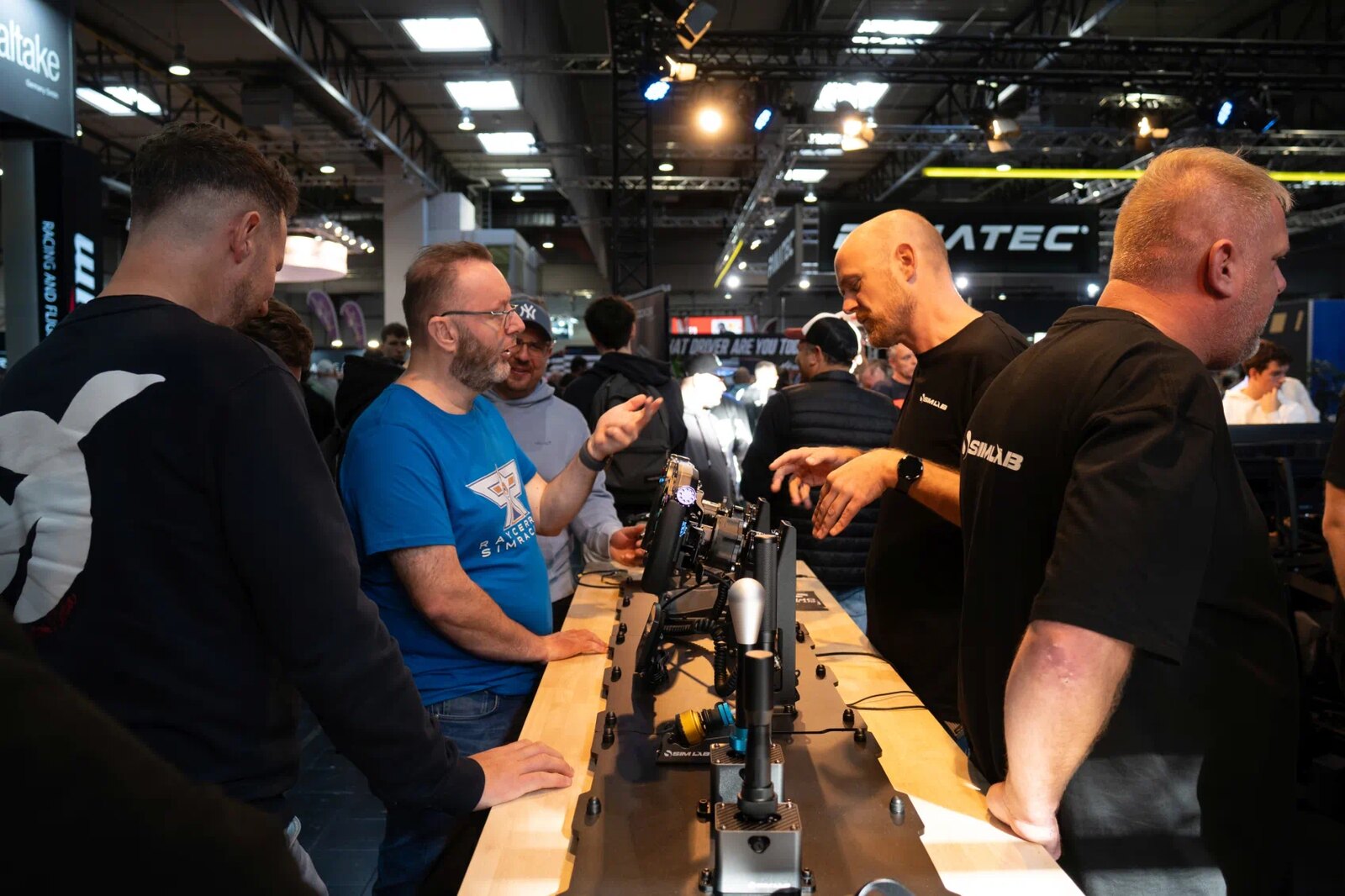 Des visiteurs essaient du matériel de simracing sur un stand du salon en 2025