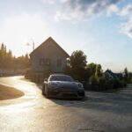 Une sportive grise dans une rue de village de l'Eifel au coucher du soleil, dans le free roam d'Assetto Corsa EVO