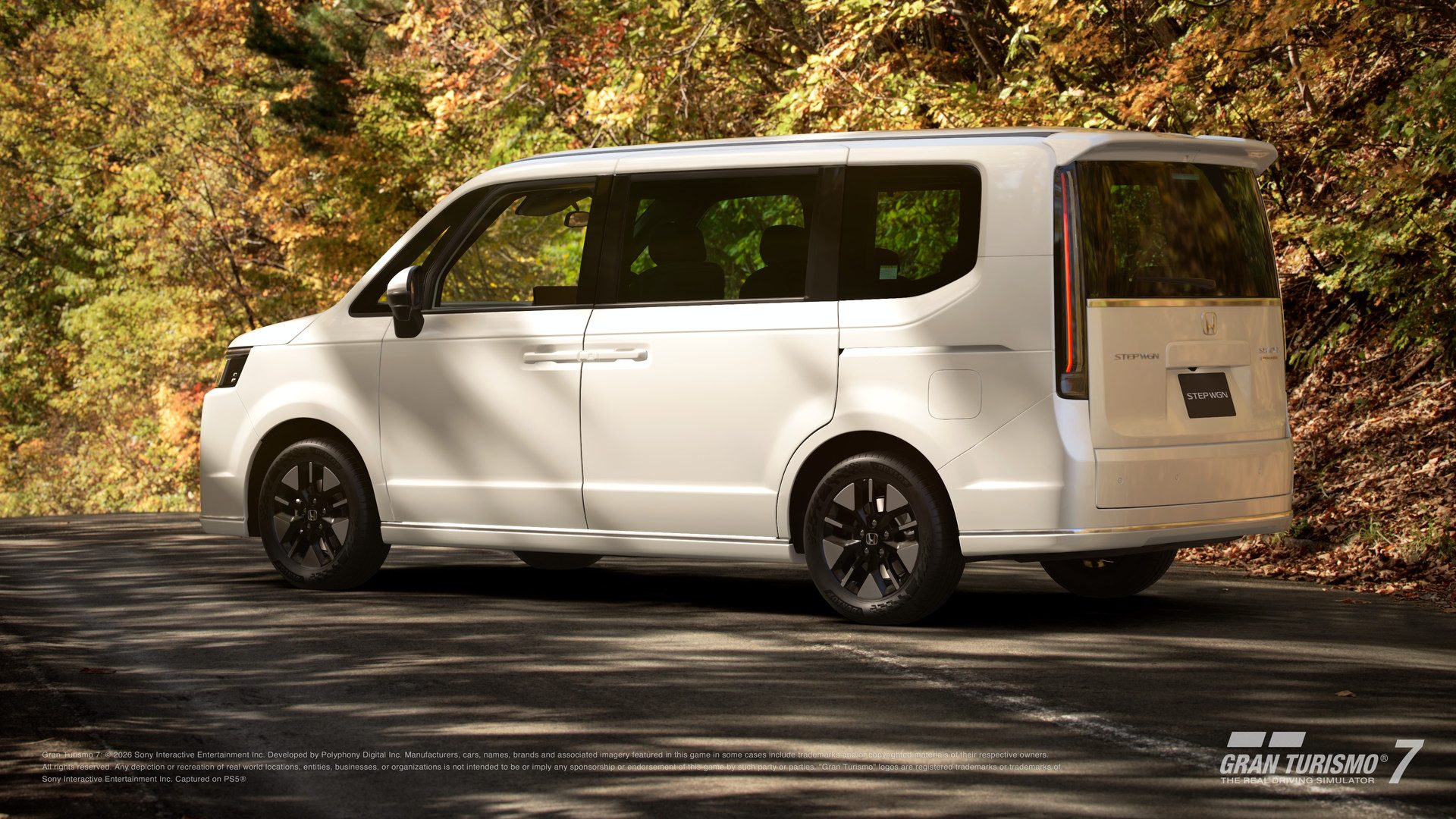 Le Honda Step WGN Spada Premium Line '23 blanc sur une route de montagne en automne